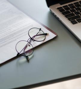 Eyeglasses on paper document, all next to a laptop.