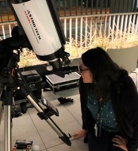 library employee enjoying looking through a telescope at Astronomy Night