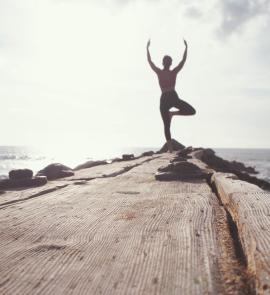 man standing while raising his hands at seashore